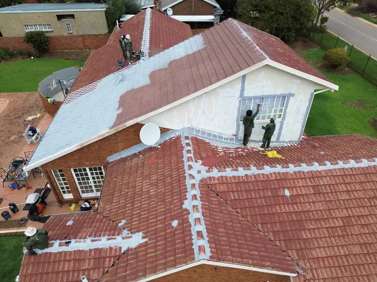 Two painters working on a white gable end