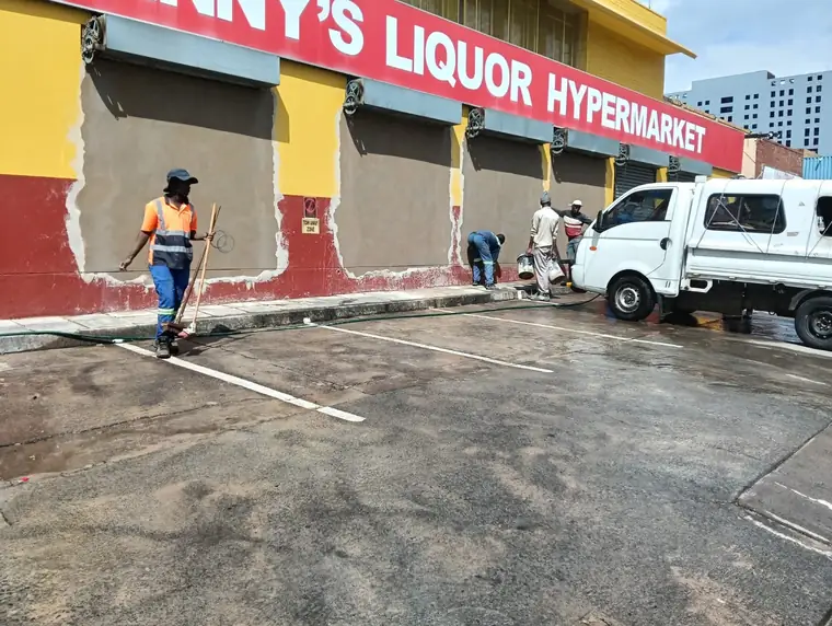 Painter working on the exterior of Johnny's Liquor Hypermarket