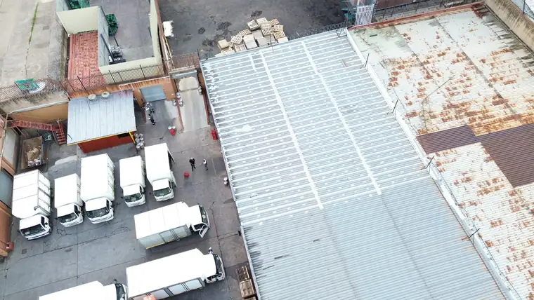 Warehouse roof with one half freshly coated white and the other half weathered